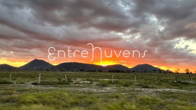Entardecer dourado sobre montanhas e campo