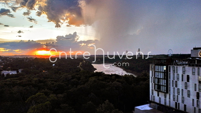 Pôr do sol dramático com tempestade sobre rio e floresta