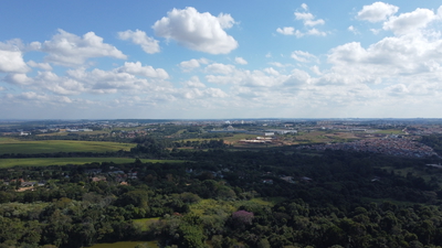 Vista aérea parcial da área urbana e rural, com grande área de céu e nuvens.