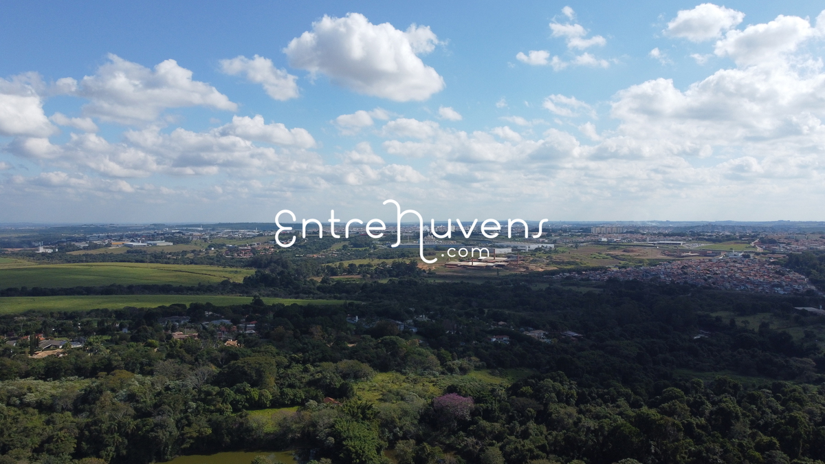 Vista aérea parcial da área urbana e rural, com grande área de céu e nuvens.